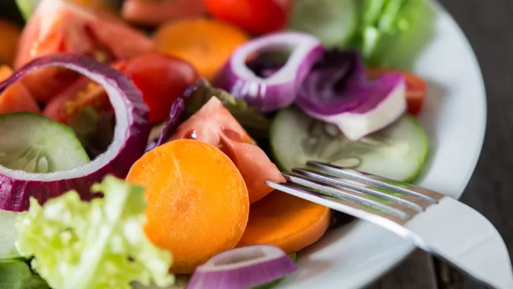 Prato de salada fresca com cenoura, tomate, pepino, alface e cebola roxa, alimentos naturais e saudáveis.